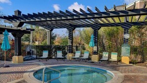 Zona de piscina con una pérgola, sillones de descanso y un cartel que prohíbe el clavado.