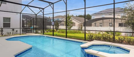 An indoor swimming pool with a clear view of the surrounding neighborhood through large windows.