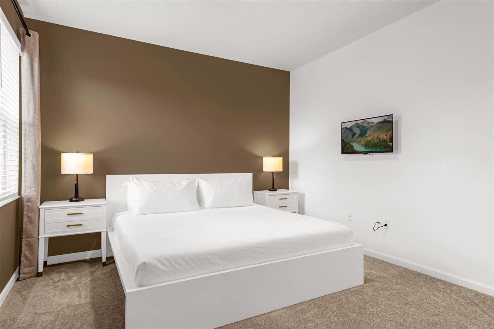 A bedroom with a large bed, two bedside tables, and a wall-mounted painting.