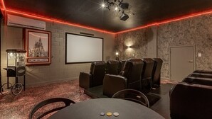 Ein Heimkino mit Projektionsleinwand, Ledersesseln, einer Popcornmaschine und einem gerahmten Bild an der Wand.