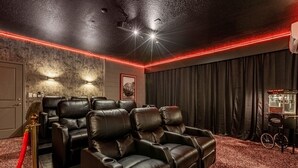 Ein Heimkino mit Ledersesseln, einer Popcornmaschine und einem roten Teppich.
