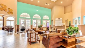 A spacious lobby with a large seating area, a reception desk, and a view of the outdoors through large windows. - Spacious 4BR Family Townhouseprivate Pool & BBQ (Kissimmee)