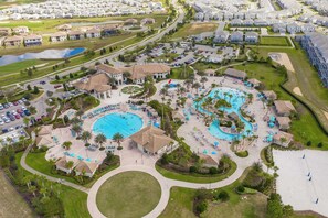 Vista aérea de un complejo turístico con varias piscinas, un pabellón central y villas circundantes.