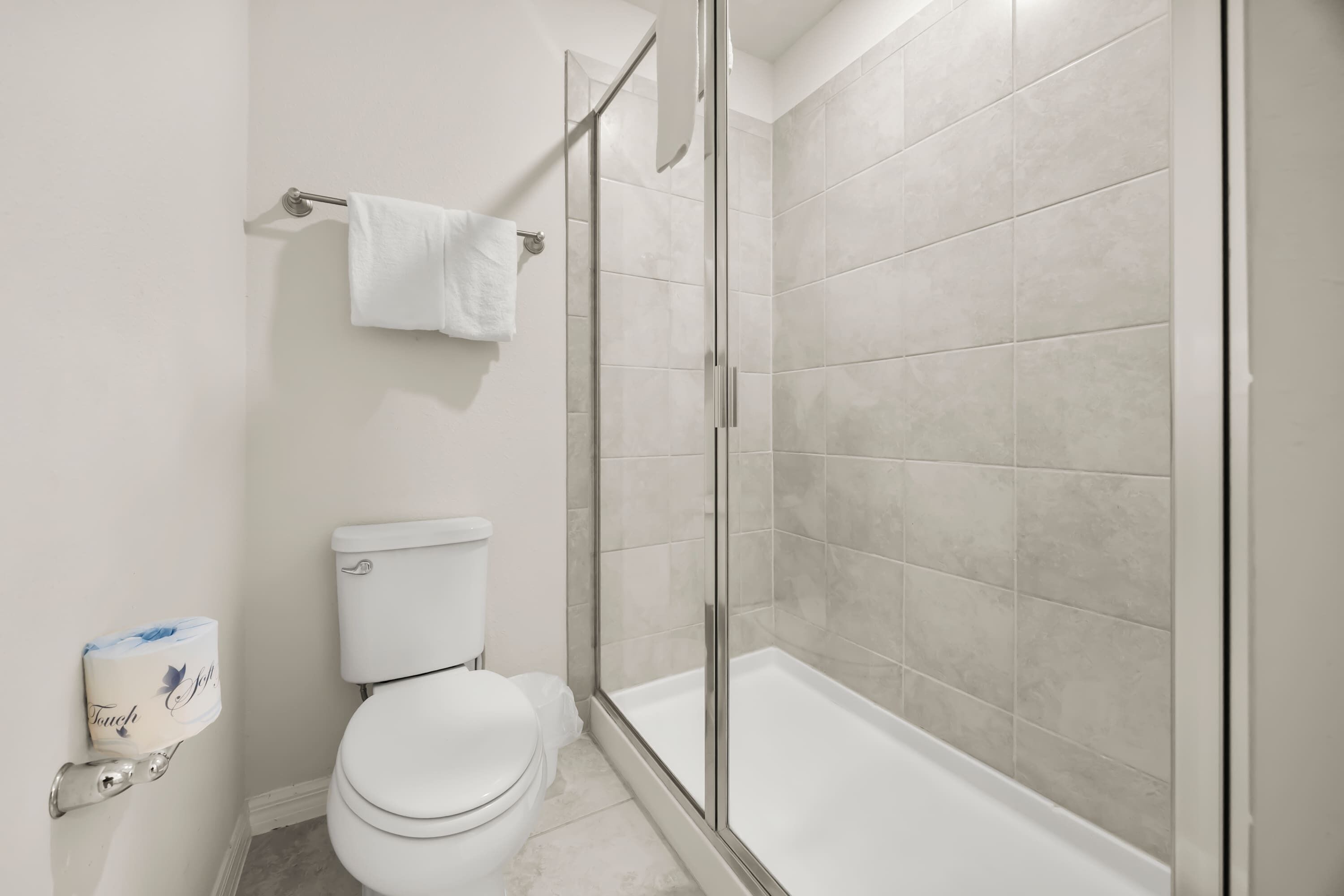 A modern bathroom with a toilet, a glass shower enclosure, and a white sink.