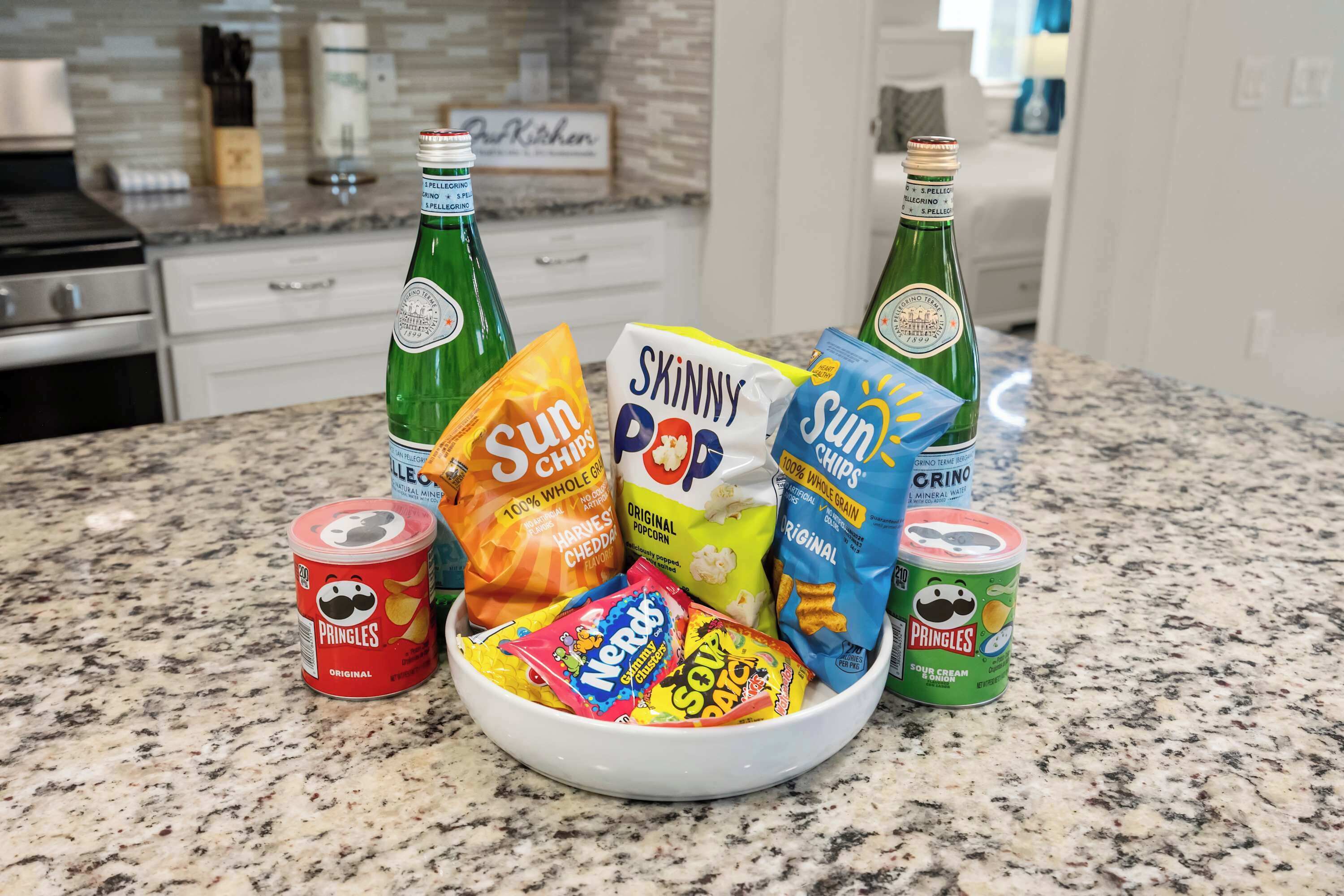 A kitchen counter with snacks, drinks, and a bowl.