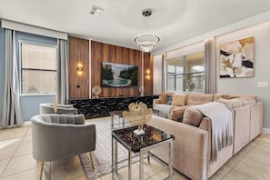 A modern living room with a sofa, armchairs, a coffee table, and a fireplace. - Upstay: Movie-themed Villa for 22 at Championsgate (Davenport)