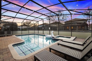 A swimming pool with lounge chairs and a swan float, surrounded by a covered patio with string lights. - Upstay: Movie-themed Villa for 22 at Championsgate (Davenport)