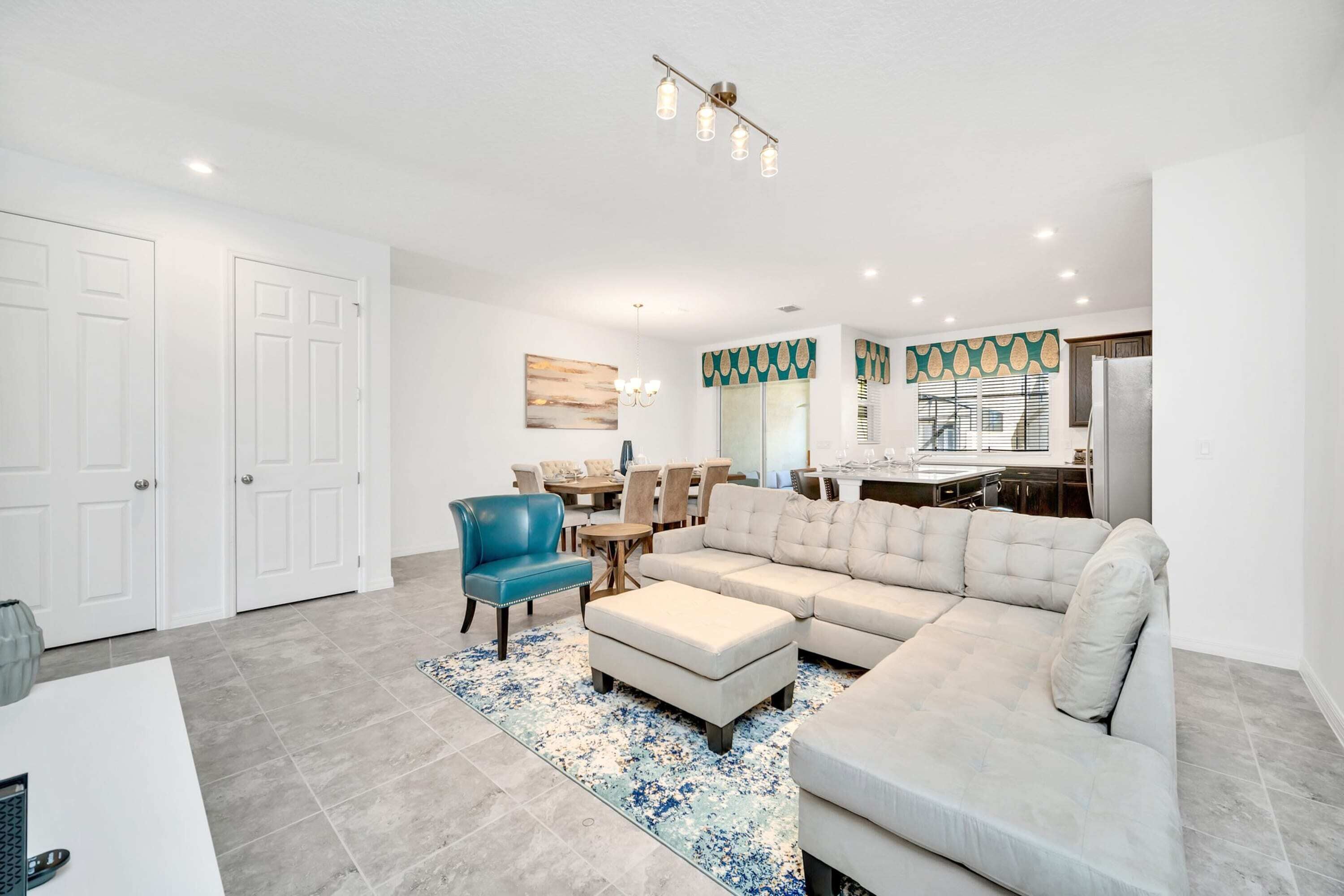 A modern living room with a sectional sofa, a blue armchair, and a dining area with a table and chairs.