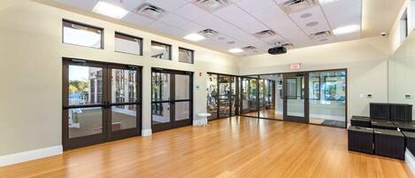 A spacious room with wooden flooring, large windows, and a ceiling with recessed lighting.