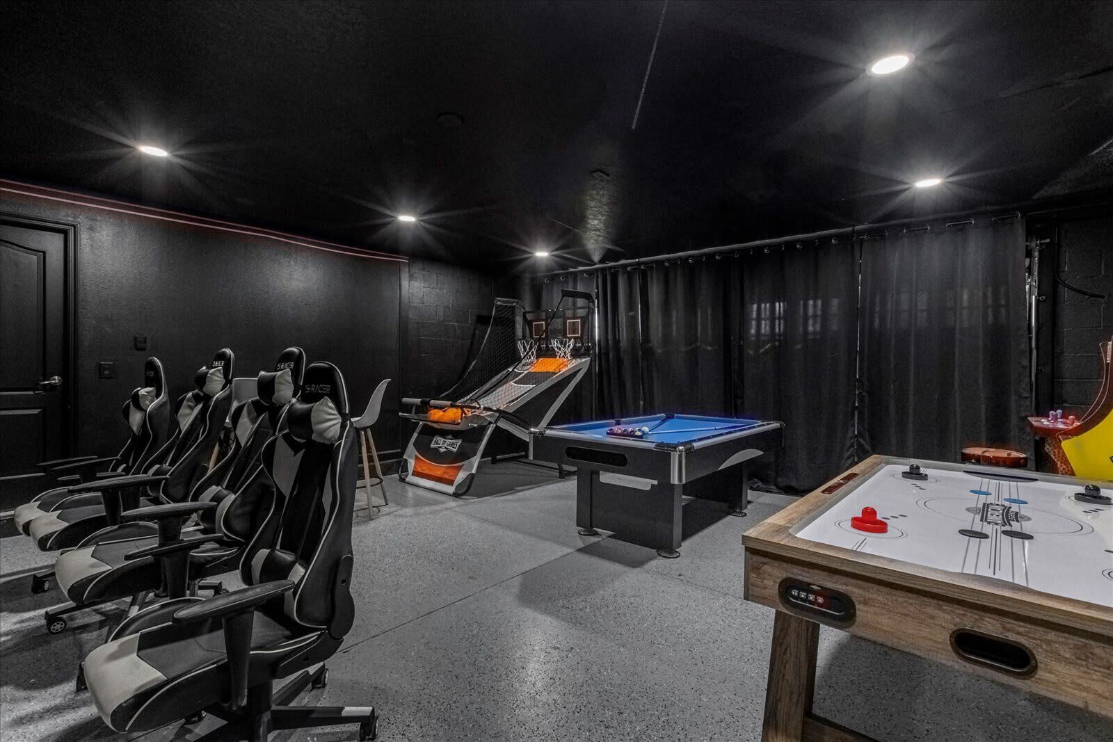 Une salle dotée de plusieurs tables de jeux, notamment de billard et de baby-foot, ainsi que de plusieurs fauteuils inclinables.