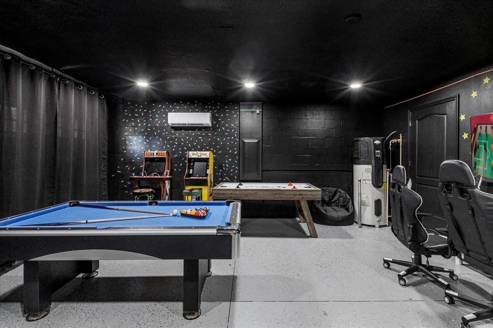 Una stanza con tavolo da biliardo, tavolo da calcio e tavolo da ping pong. Sono presenti due sedie e un sacco da boxe.