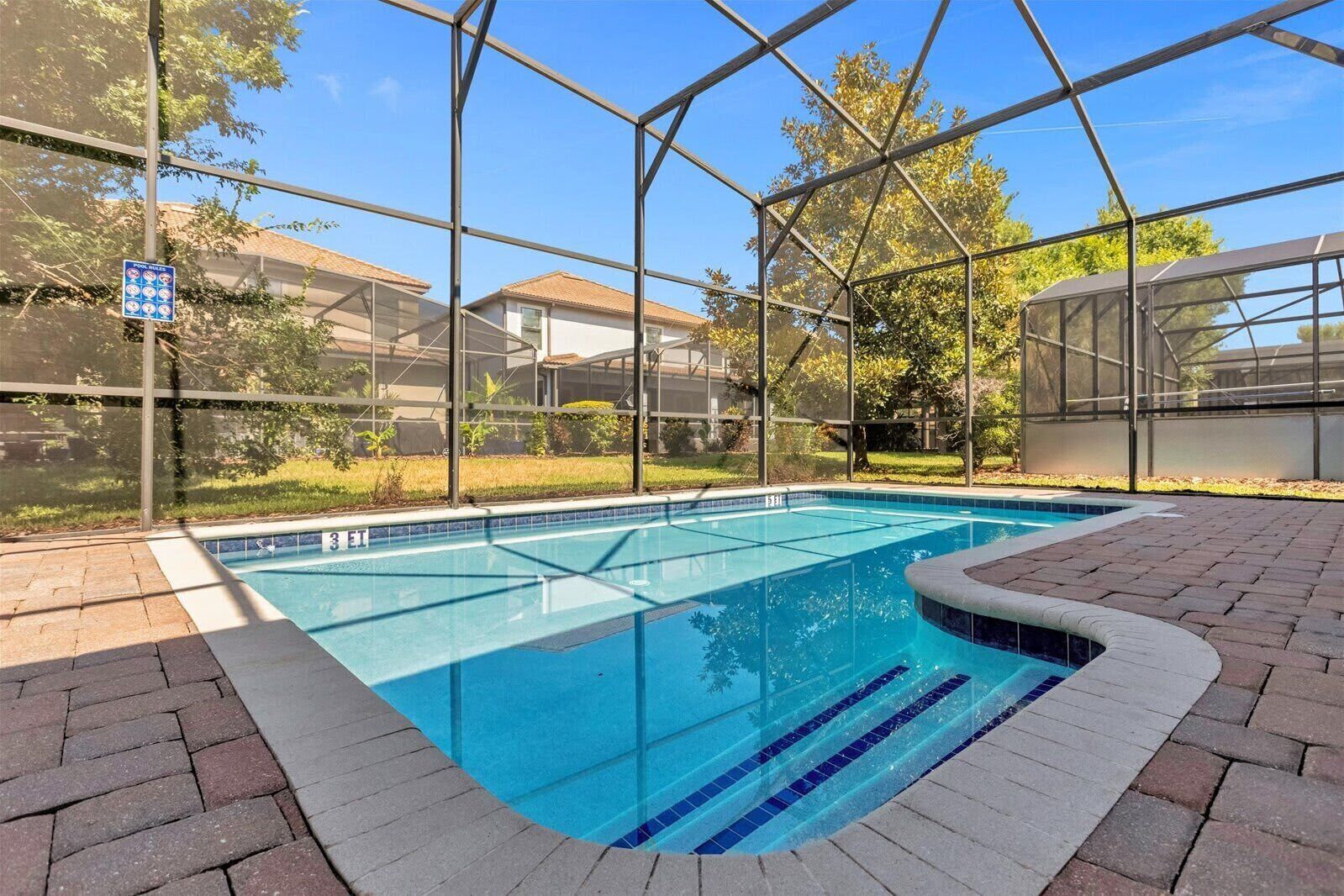 Ein überdachter Pool mit klarem, blauem Wasser, umgeben von einer Glaskonstruktion und Fliesenböden.