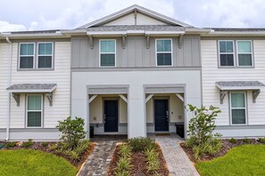 A two-story residential building with a symmetrical facade, a central entrance with double doors, and a small porch area. - Upstay Family Fun 5BR Retreat w Pool & Games Room (Clermont)