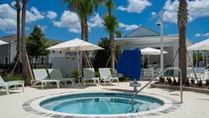A pool area with lounge chairs and umbrellas, surrounded by palm trees and a covered seating area. - Upstay Family Fun 5BR Retreat w Pool & Games Room (Clermont)