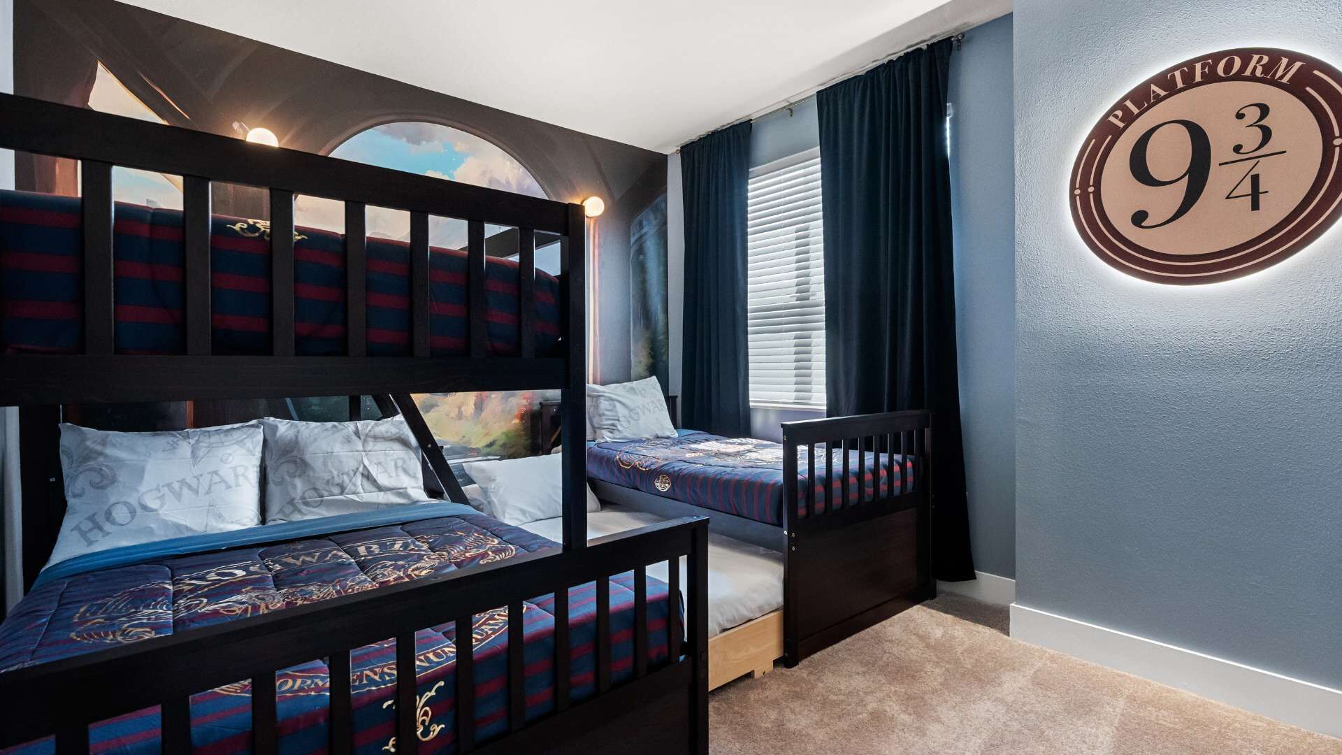 A bedroom with bunk beds, a circular wall decoration, and a window with blinds.
