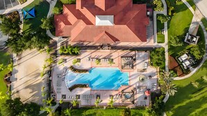 Ein Luftbild eines Hotels mit Schwimmbad, Liegebereichen und angelegten Gärten.