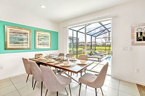 Uma sala de jantar com mesa posta para seis, um espaço envidraçado e vista para o exterior.