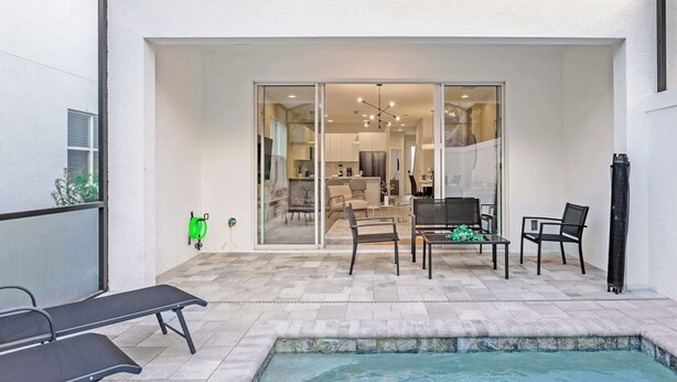 A pool area with a hot tub, lounge chairs, and a dining area with chairs and a table.