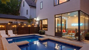 En baghave med swimmingpool, en terrasse med udendørs møbler, og en glasindhegnet patio.