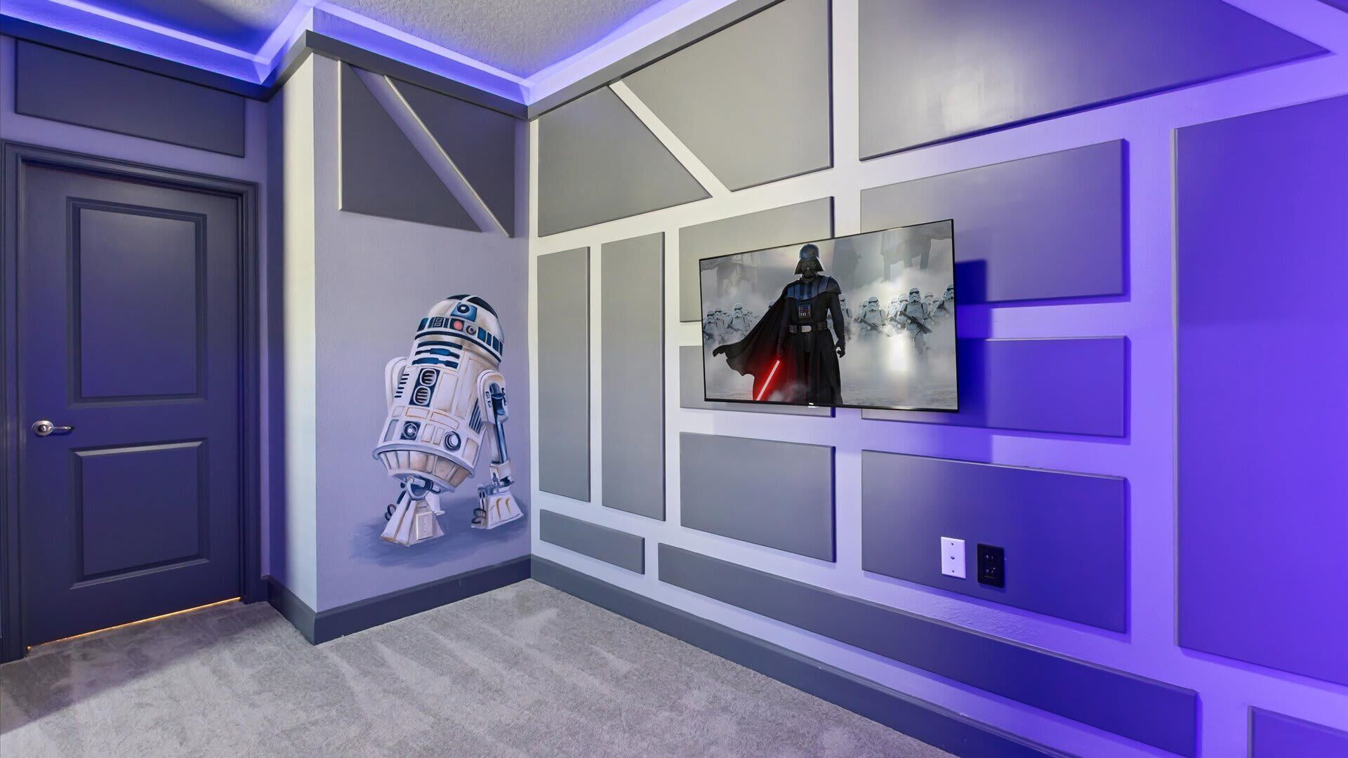 A hallway with a grey door, a wall-mounted Star Wars-themed artwork, and a Star Wars character cutout.