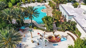 A resort with a central swimming pool, palm trees, and a decorative ship. - Upstay Family Getaway With Pool Near Disney (Davenport)