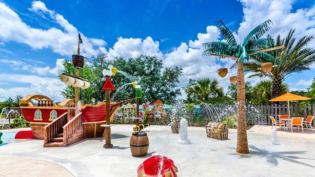 A water park with a pirate ship, palm trees, and a sandy play area. - Upstay Family Getaway With Pool Near Disney (Davenport)