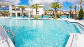 Ein Swimmingpool mit Liegestühlen und Palmen, umgeben von Gebäuden.