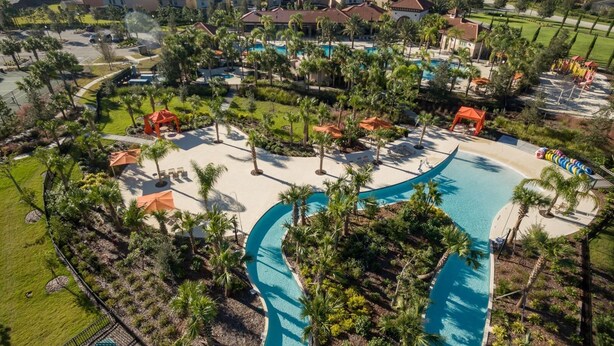 Un resort con una grande piscina, palme e vista sulle case circostanti.
