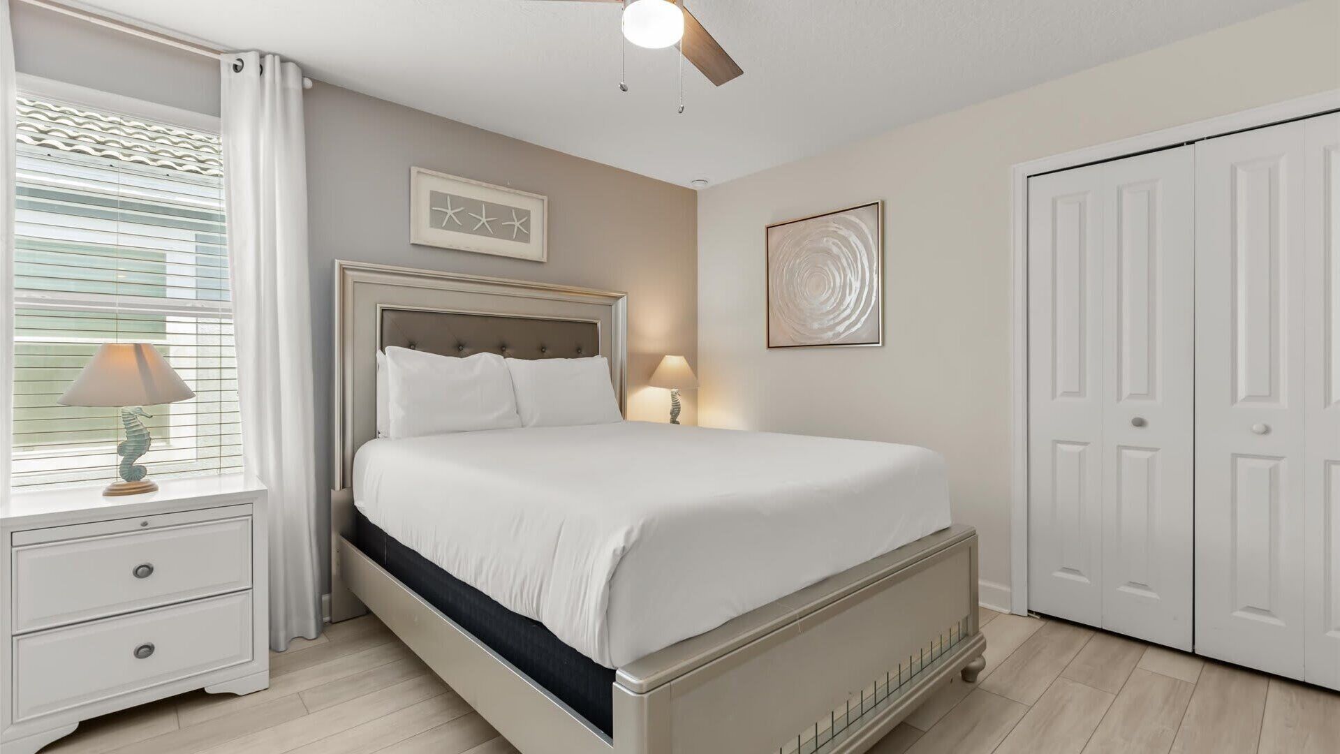 A bedroom with a bed, bedside tables, a ceiling fan, and a wardrobe.