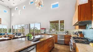 A spacious kitchen with granite countertops, stainless steel appliances, and wooden cabinetry. - Luxury 7BR Hill Country Gem With Barndominium (Dripping Springs)