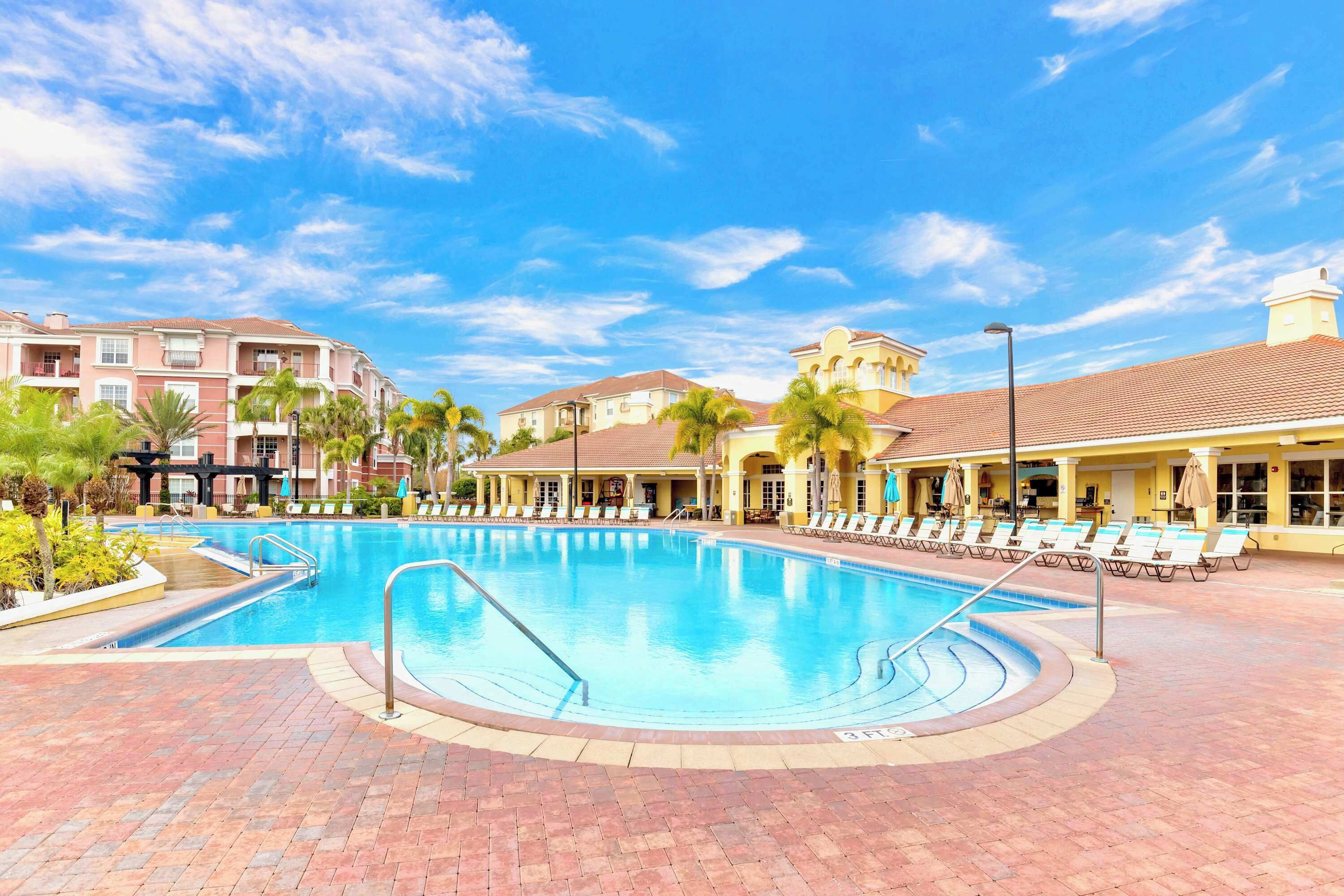 A swimming pool with lounge chairs and a brick walkway.