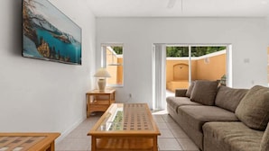 A living room with a sofa, a coffee table, a painting, a lamp, and a view through a sliding door to an outdoor area. - Family Retreat at Terra Verde Resort Near Disney (Kissimmee)