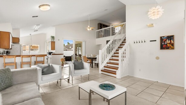 A spacious living area with a white staircase, a dining area, and a kitchen. - Upstay: Bright Family-friendly Retreat With Patio (Kissimmee)