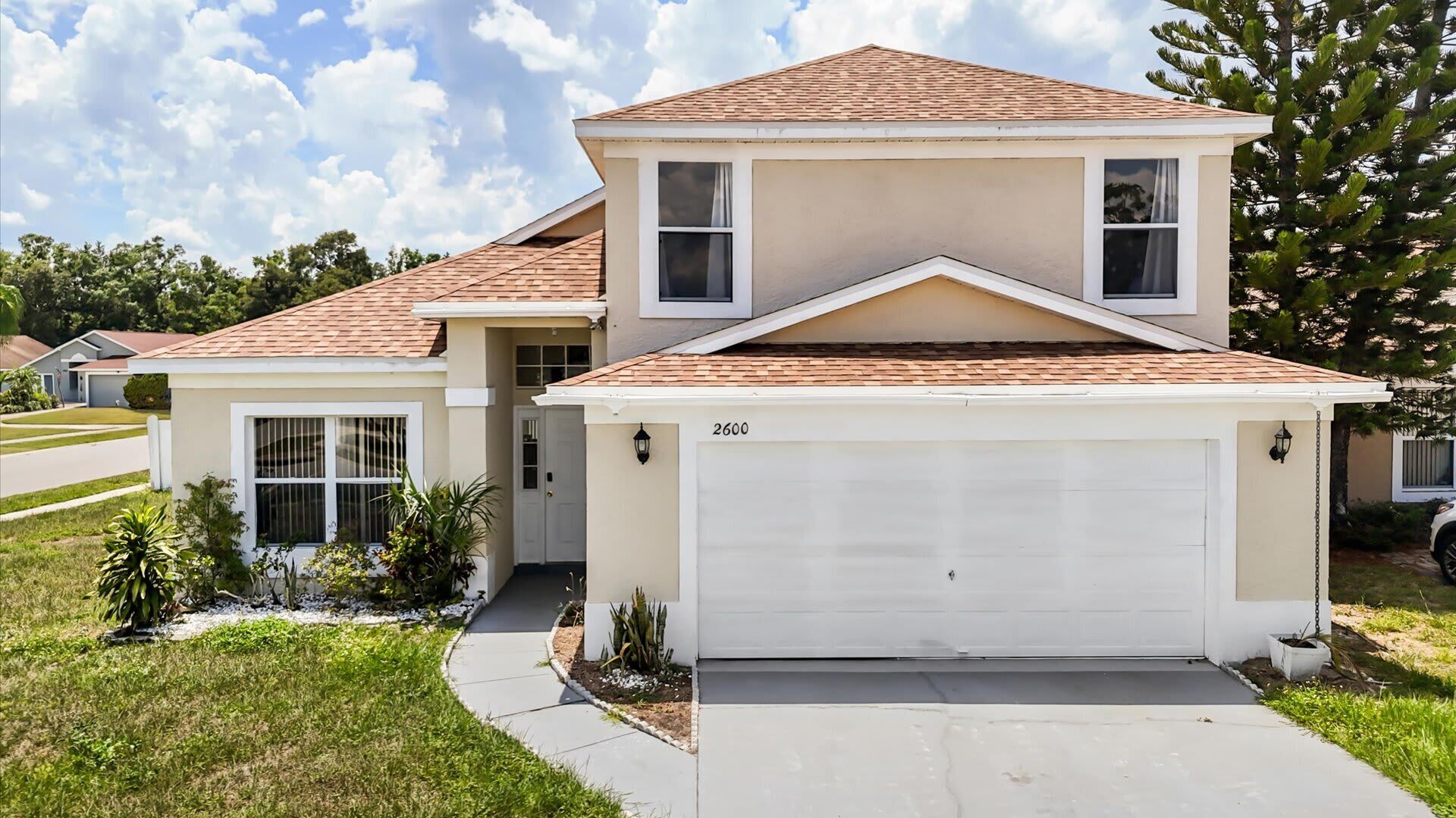 A two-story house with a garage, a driveway, and a well-maintained lawn.