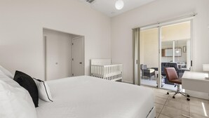 A modern hotel room with a large bed, a desk, and a chair. There is a sliding glass door leading to a balcony with outdoor seating. - Upstay: Bright Family-friendly Retreat With Patio (Kissimmee)