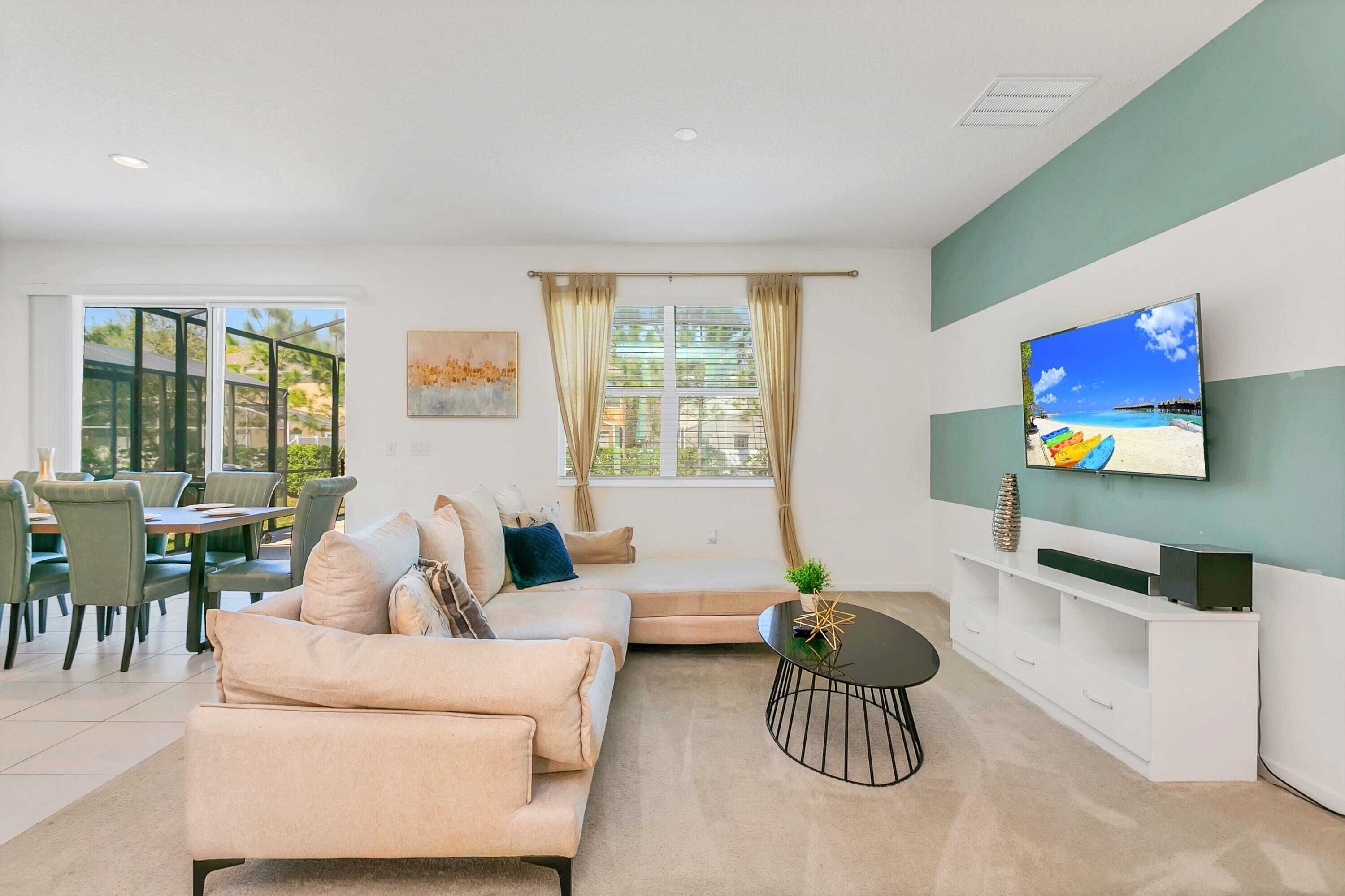Una sala de estar moderna con un sofá color beige, una mesa de centro y un televisor de pantalla plana montado en la pared.