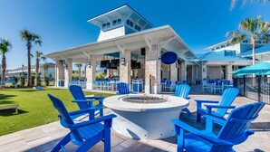 A poolside area with blue Adirondack chairs, a fire pit, and a covered seating area with tables and chairs. - Upstay: Modern Windsor Resort Home Near Disney (Davenport)