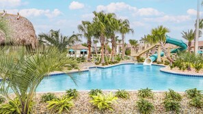A swimming pool with a slide, palm trees, and a thatched roof structure. - Upstay: Luxury 4BR Family Home w Poolnear Disney (Davenport)
