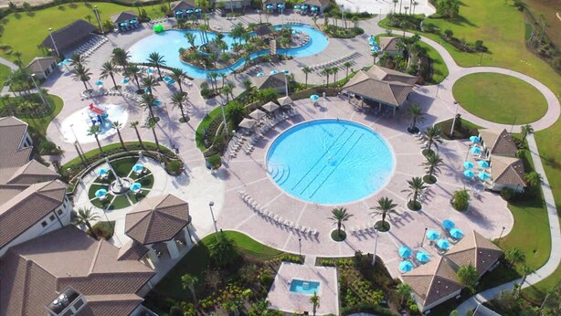 An aerial view of a resort with multiple swimming pools, sun loungers, and palm trees. - Upstay: Luxury 4BR Family Home w Poolnear Disney (Davenport)