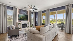 Una sala de estar moderna con chimenea, televisor grande y vistas al exterior.