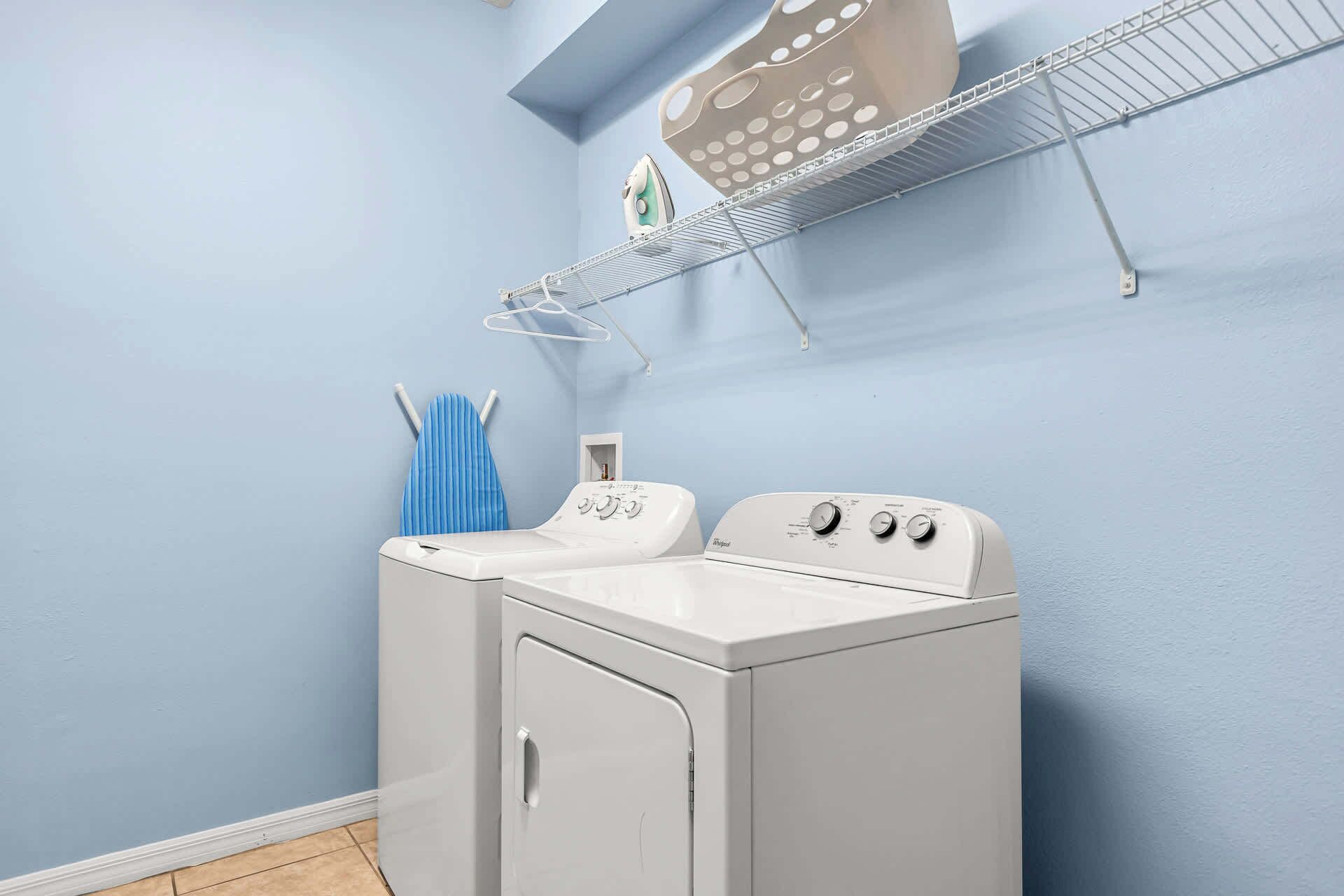 A compact, white front-loading washer and dryer unit in a laundry room with light blue walls.