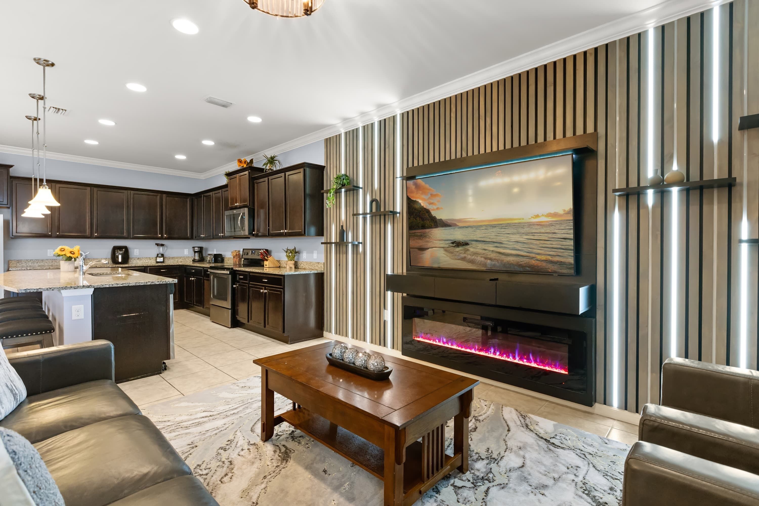 A modern kitchen with dark cabinets, a central island, and a built-in oven.