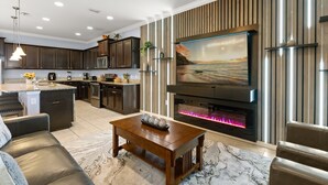 A modern kitchen with dark cabinets, a central island, and a built-in oven. - Upstay Family Retreat w Pool, Theater & Games Room (Kissimmee)