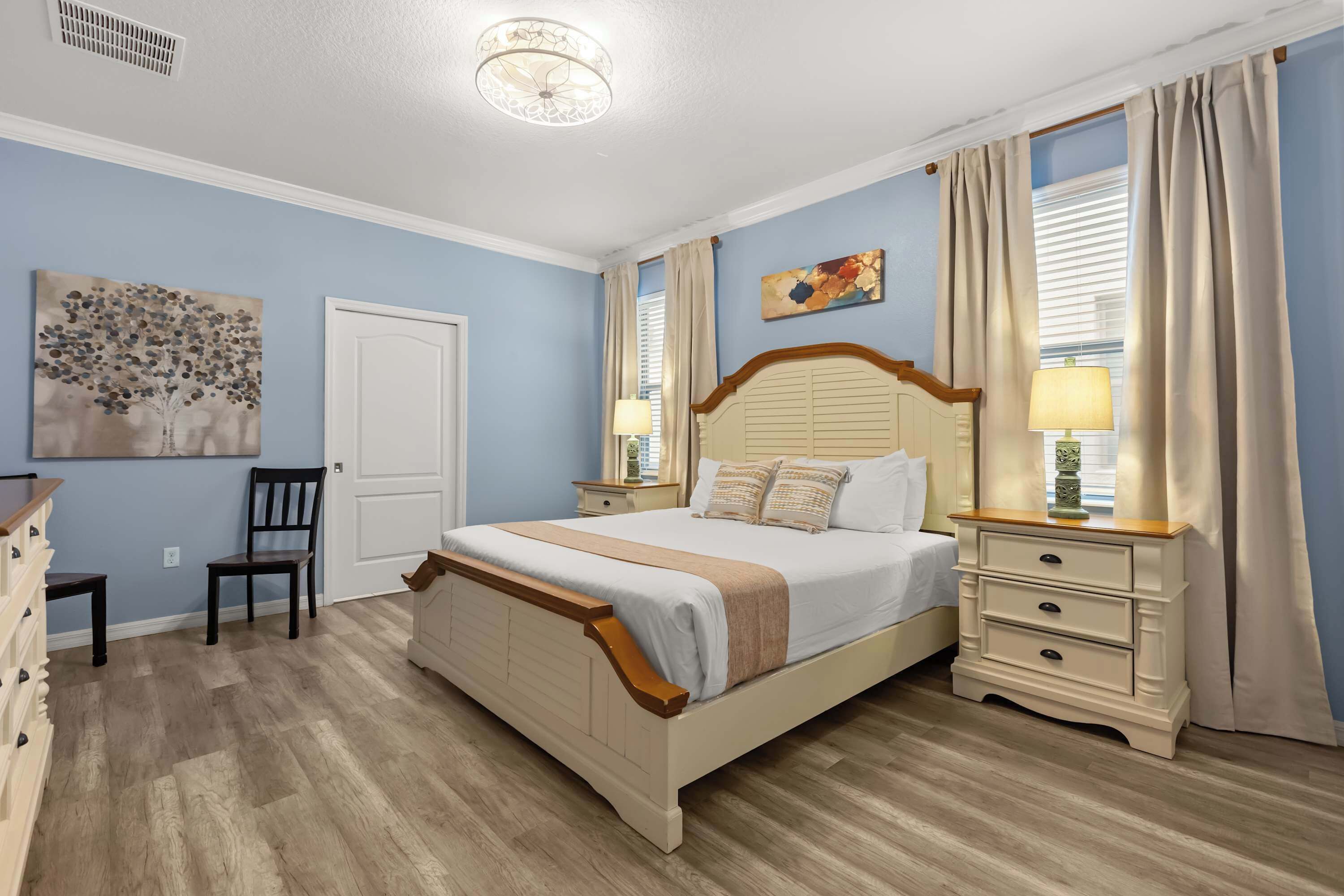 Un dormitorio con cama, mesitas de noche, cómoda y silla.