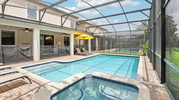 A swimming pool area with a glass-enclosed structure, lounge chairs, and a covered seating area. - Upstay: Family Home w Pool & Cinemachampionsgate (Davenport)