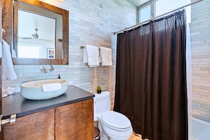 A bathroom with a round sink, a toilet, a shower curtain, and a mirror. - Luxury Hilltop Villa With Hot Tub & Scenic Views (Dripping Springs)