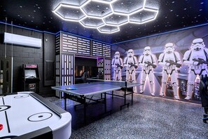 A room with a ping pong table, Star Wars-themed wall art, and a hexagonal ceiling light fixture. - Upstay Championsgate Villa With Pool and Cinema (Davenport)