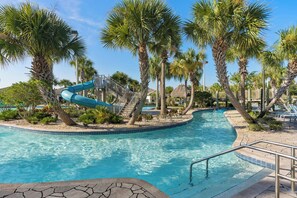 A swimming pool with a water slide, palm trees, and a thatched-roof structure. - Upstay Championsgate Villa With Pool and Cinema (Davenport)