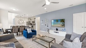 Una sala de estar moderna con un sofá azul, un sofá gris, una mesa de centro y un televisor en la pared.