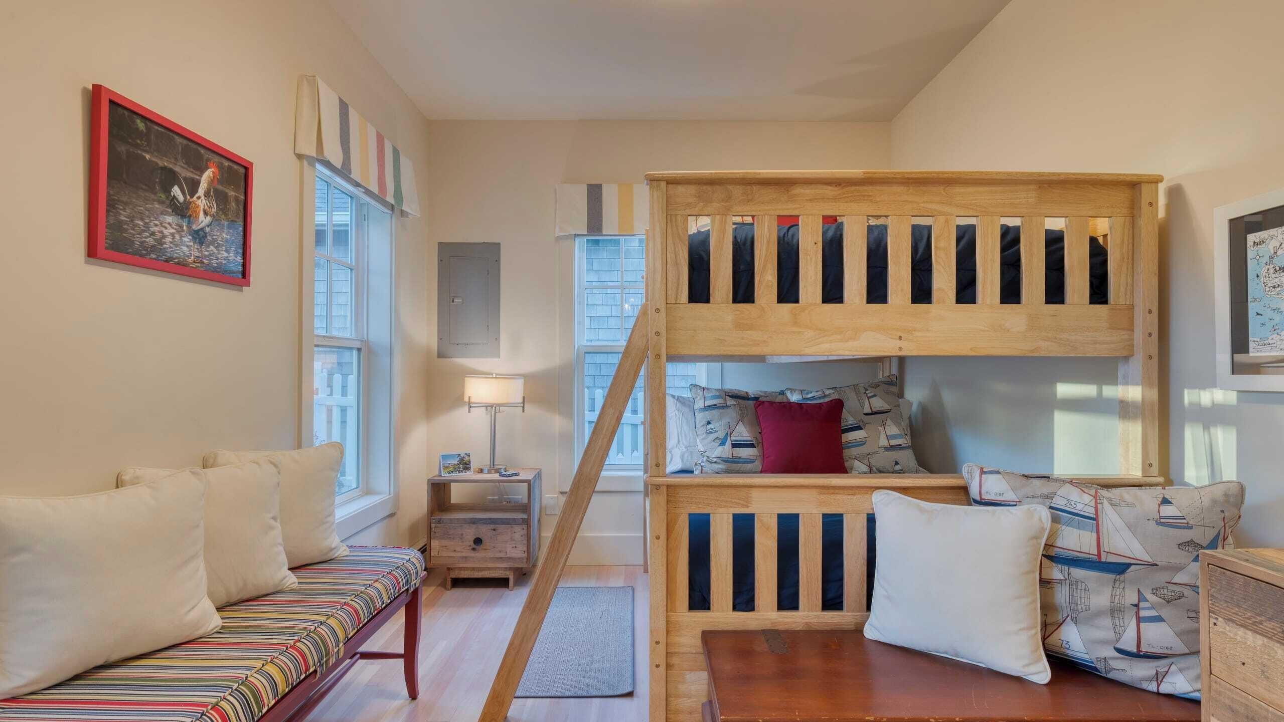 Une pièce chaleureuse avec un lit superposé, un canapé à rayures, une petite table et une lampe.